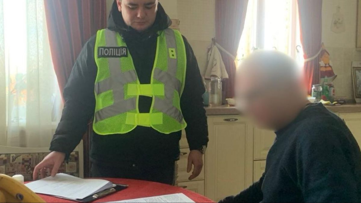 Поліцейський у жовтому жилеті складає документи поруч із підозрюваним у справі про медичну халатність лікаря у Києві