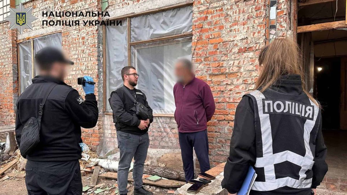Поліцейські Національної поліції проводять слідчі дії з затриманим чоловіком біля цегляної будівлі у Києві