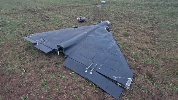 Залишки збитого дрона з чорним корпусом у формі крила, що лежить на полі