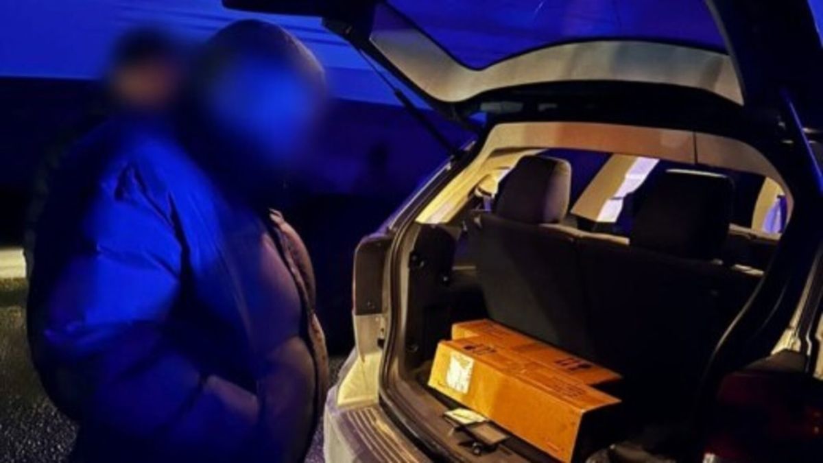 Чоловік стоїть біля відчиненого багажника автомобіля