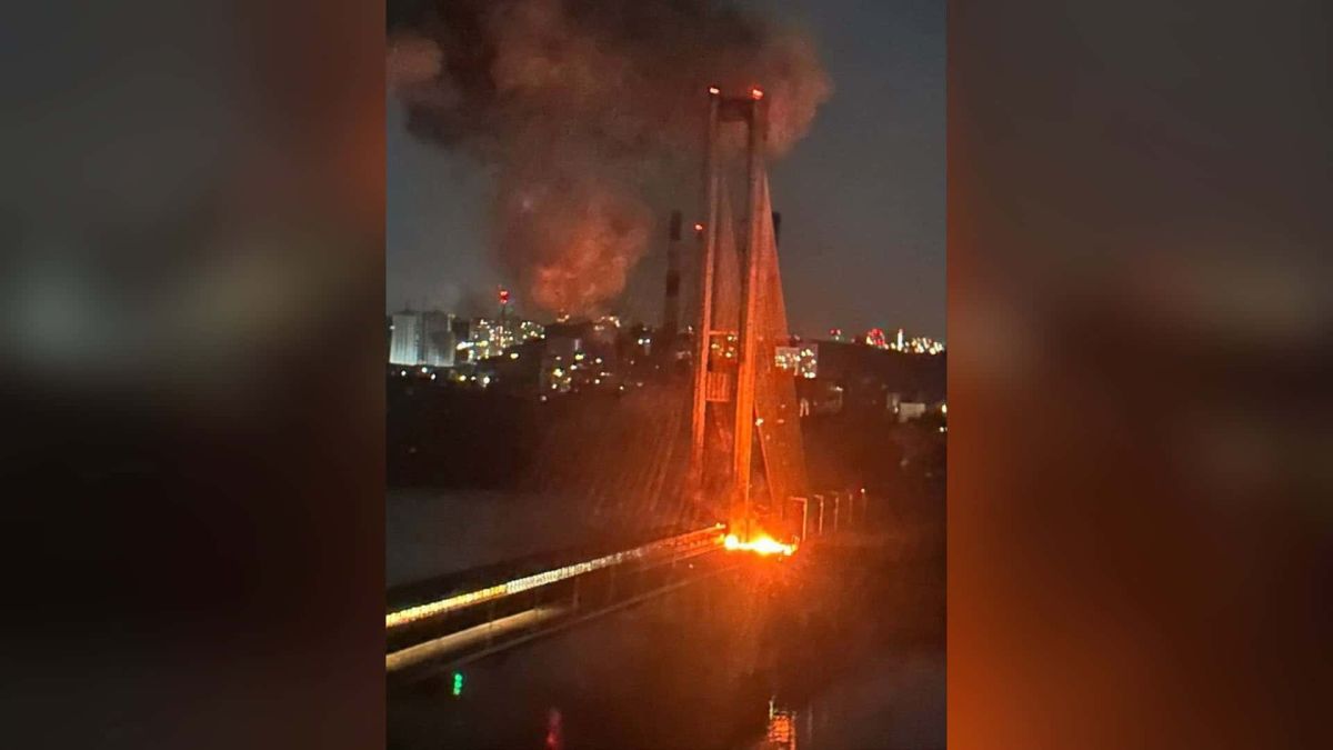 Вогонь на проїжджій частині Південного мосту в Києві біля пілона вночі після удару безпілотника, над містом здіймається дим