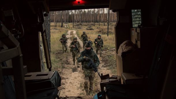 Пʼятеро військових ідуть військове авто після бойової роботи в лісосмузі