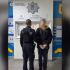 Поліцейський веде затриманого в кайданках із заблюреним обличчям у відділі поліції на Київщині