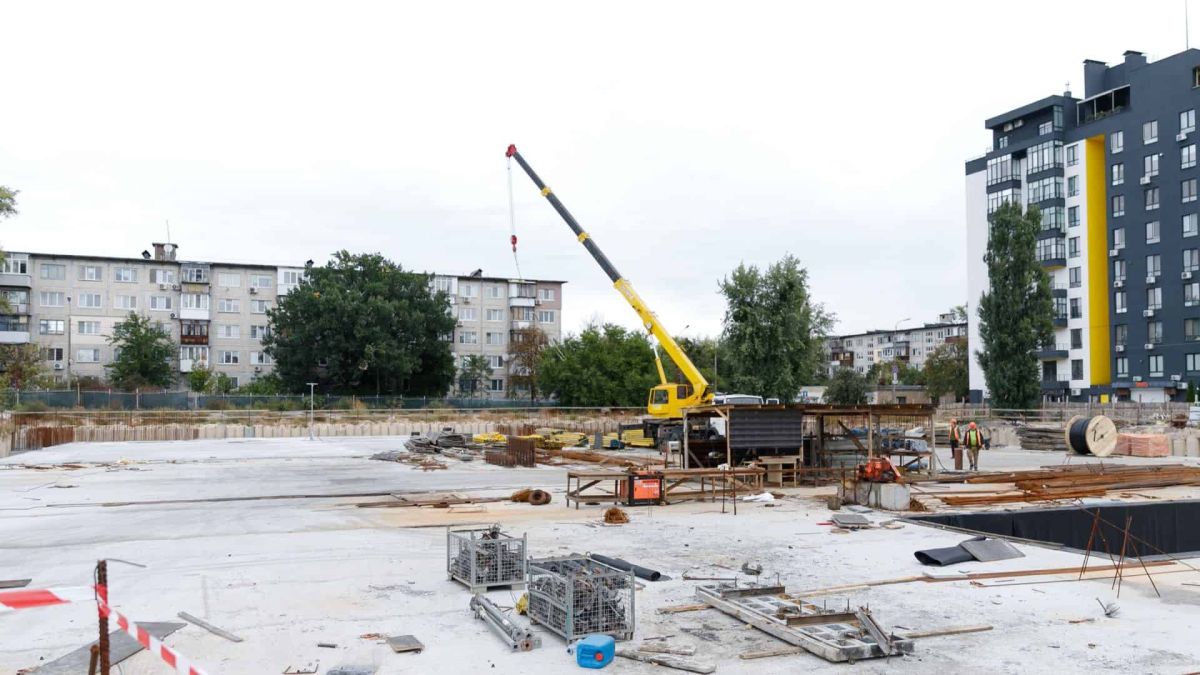 Загальний вигляд будмайданчика укриття з краном та робітниками серед будівельних матеріалів