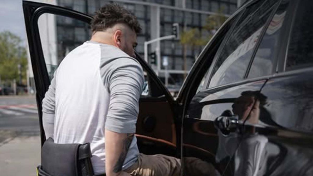 Чоловік з інвалідність з колісного крісла пересідає в автомобіль на місце водія