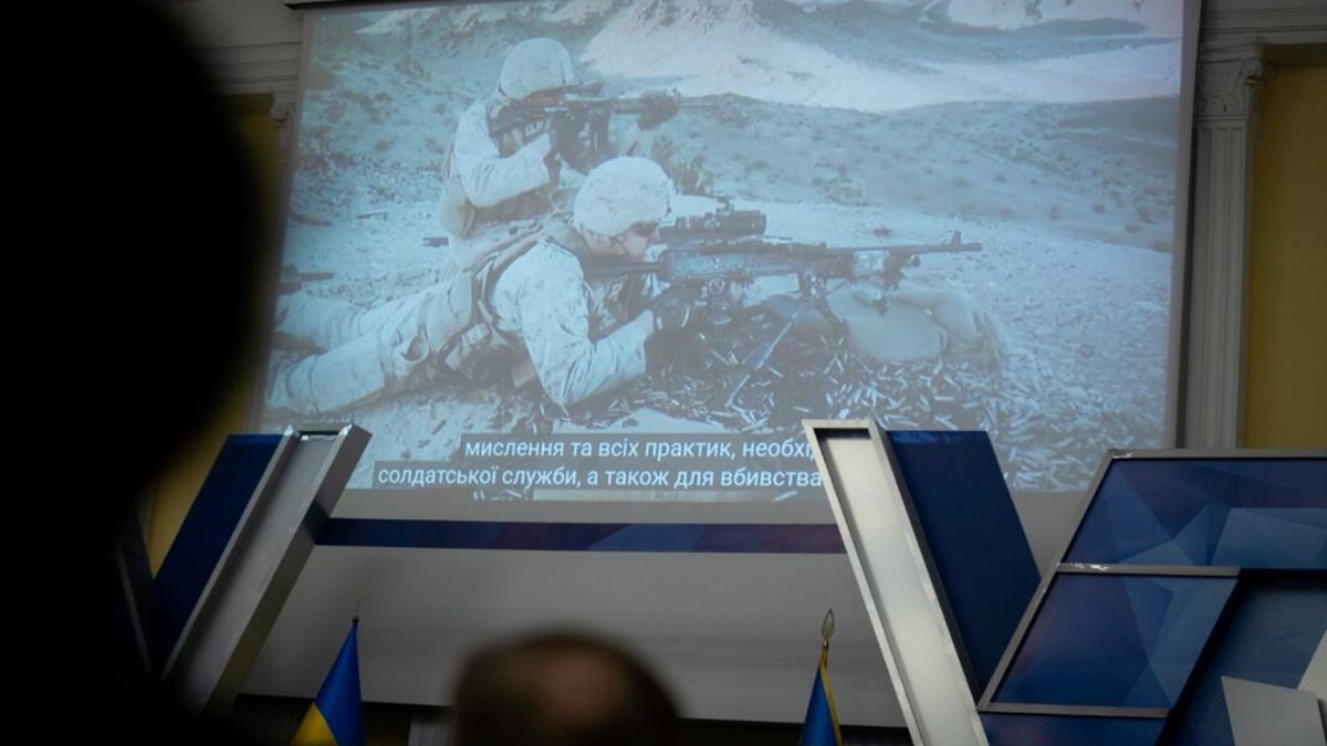 Що подивитися на Одеському кінофестивалі у Києві Глядачі дивляться кінопоказ на великому екрані: кадр із солдатами з субтитрами, поруч прапори України