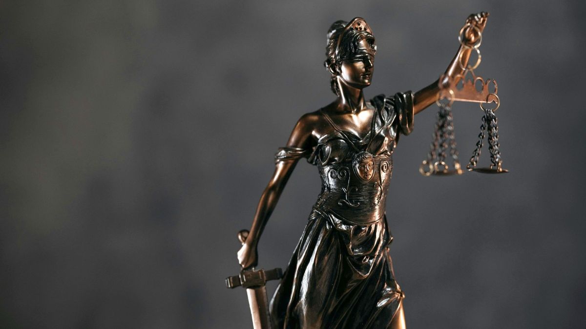 Статуетка богині Феміди з пов'язкою на очах і терезами правосуддя на столі, ілюстративне фото