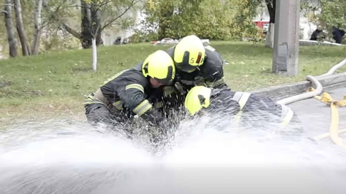 Троє рятувальників намагаються приборкати струмінь води