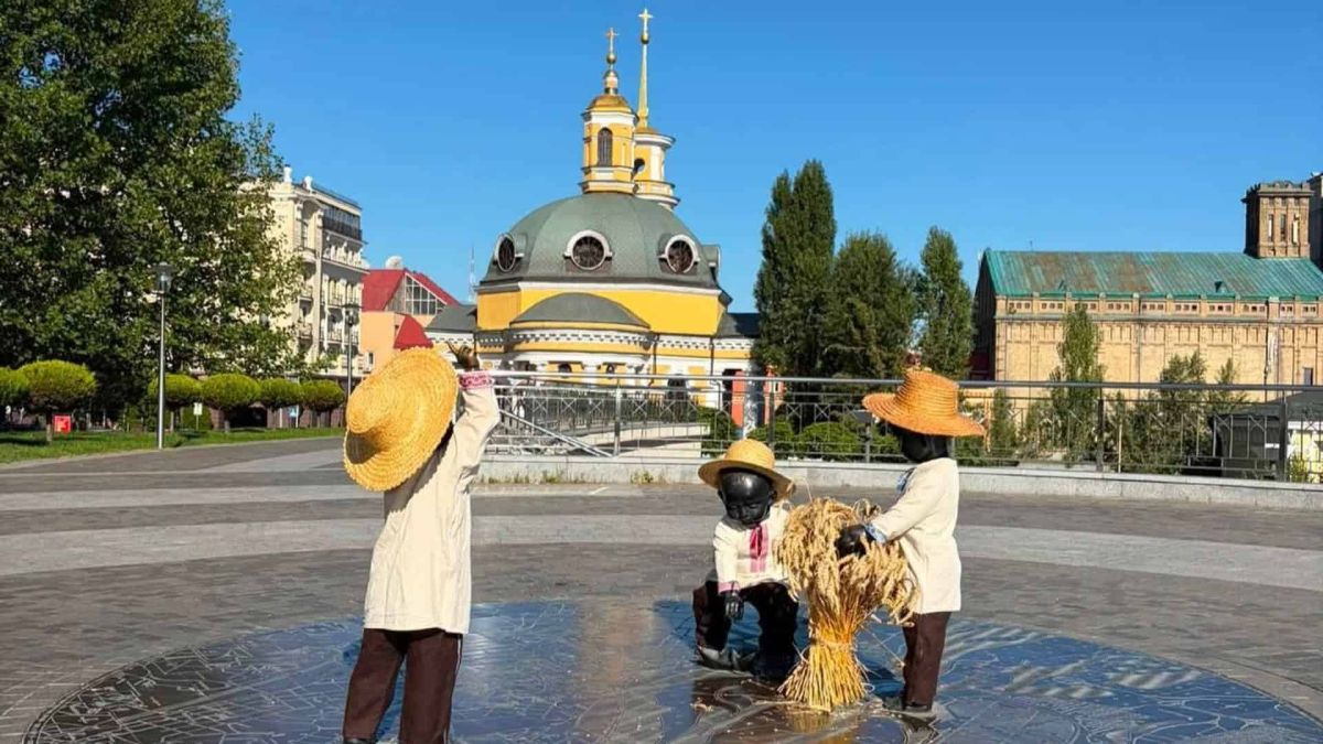 Скульптурна композиція «Малюки-засновники» на Поштовій площі в Києві одягнена в солом’яні капелюхи та вишиванки до свята Обжинок, на тлі церкви