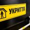 Чорні двері укриття з жовтою табличкою «Укриття» та сходами, що ведуть до захисної споруди