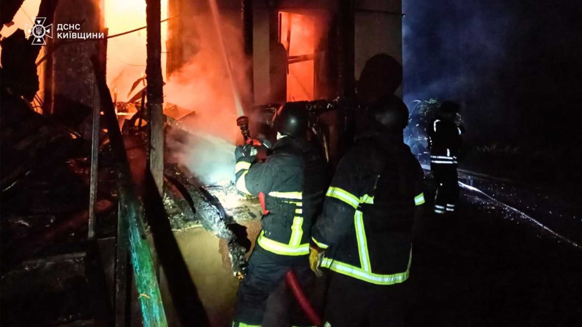 три пожежника біля палаючої будівлі
