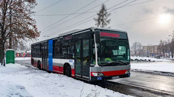 Автобус Київпастрансу маршруту 119 на засніженій зупинці в Києві взимку, на задньому плані міська забудова