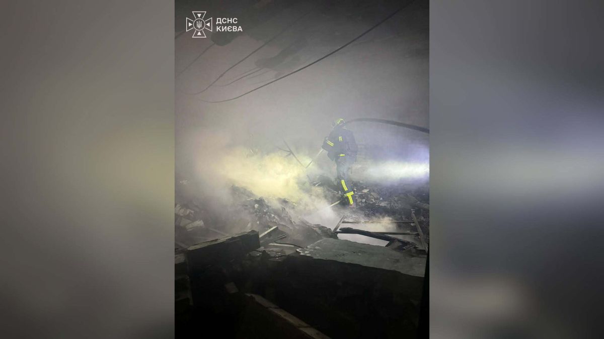Рятувальник ДСНС Києва гасить пожежу серед уламків у задимленому приміщенні після атаки на столицю