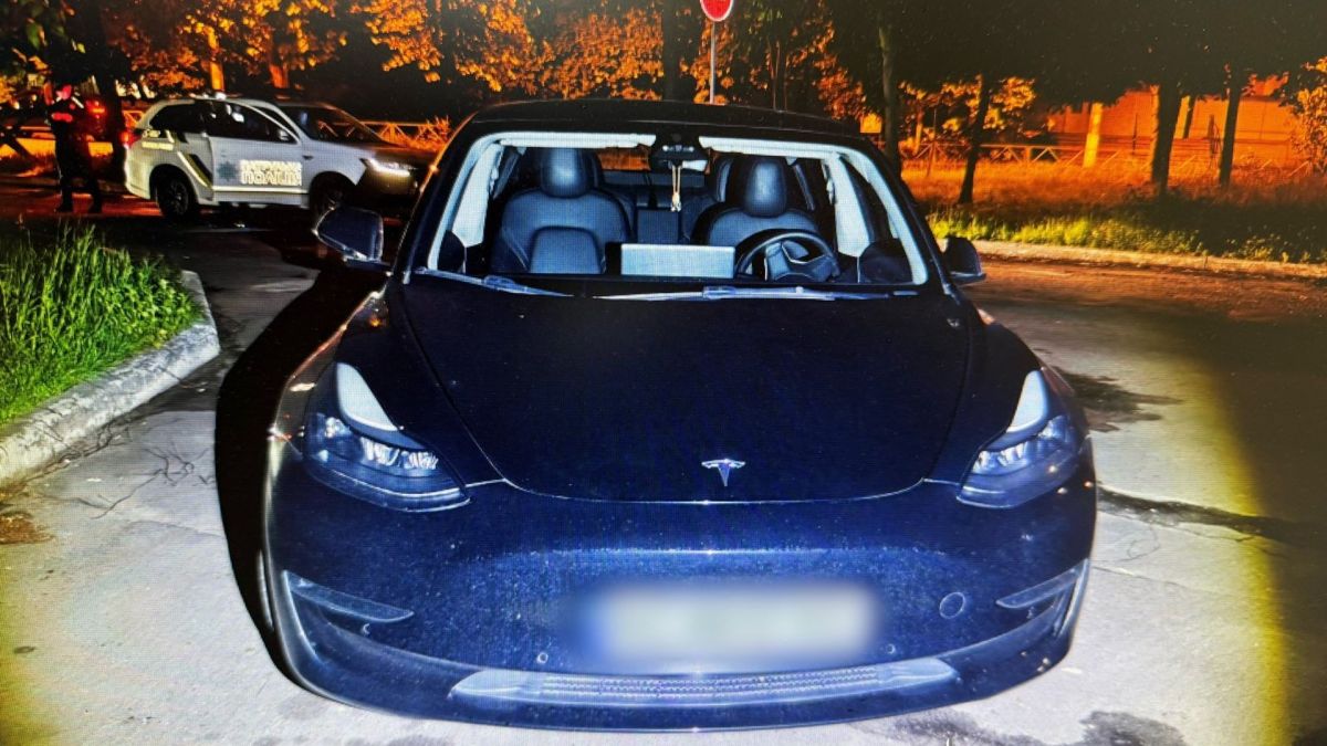 Вкрадений автомобіль Tesla на АЗС в Оболонському районі Києва — кадр поліції після затримання підозрюваного
