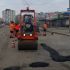 Дорожня техніка та робітники у помаранчевих жилетах ремонтують аварійні ділянки дорожнього покриття на вулиці Хрещатик у Києві
