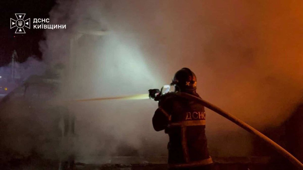 Рятувальник у захисному спорядженні спрямовує струмінь води на осередок задимлення після атаки на Київщину