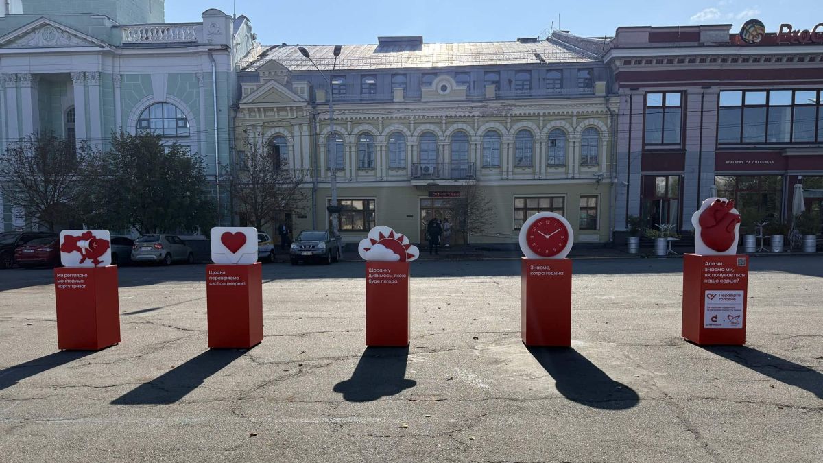 На Контрактовій площі у Києві відкрили інсталяцію про здоров’я серця Червоні тумби з символами: карта тривог, лайк, погода, годинник і серце — інсталяція на Контрактовій площі у Києві