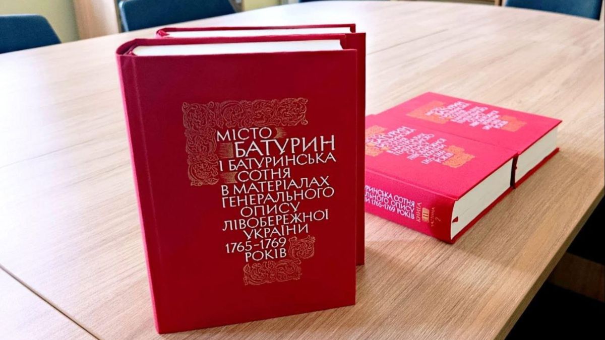 Два томи археографічного видання «Місто Батурин і Батуринська сотня» в червоних палітурках на дерев'яному столі