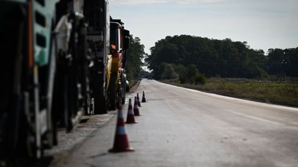 Ремонт дороги: будівельна техніка та конуси обмежують рух на асфальтованій ділянці серед полів і дерев