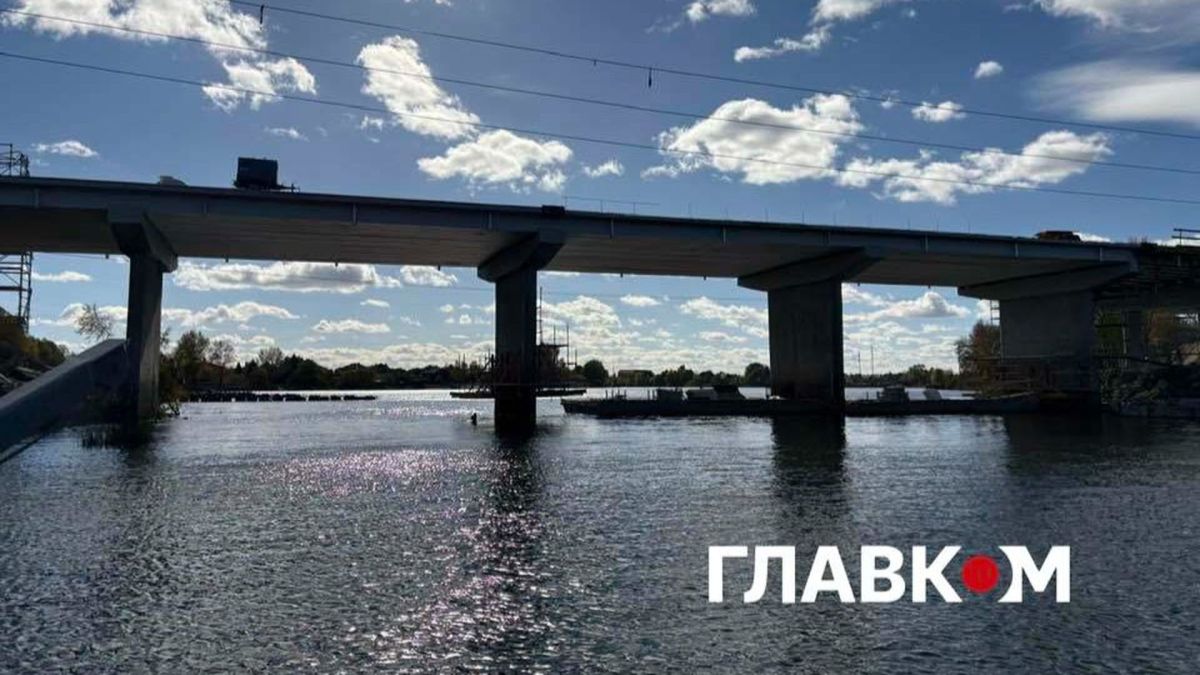 Автомобільний міст через річку з бетонними опорами під блакитним небом з білими хмарами