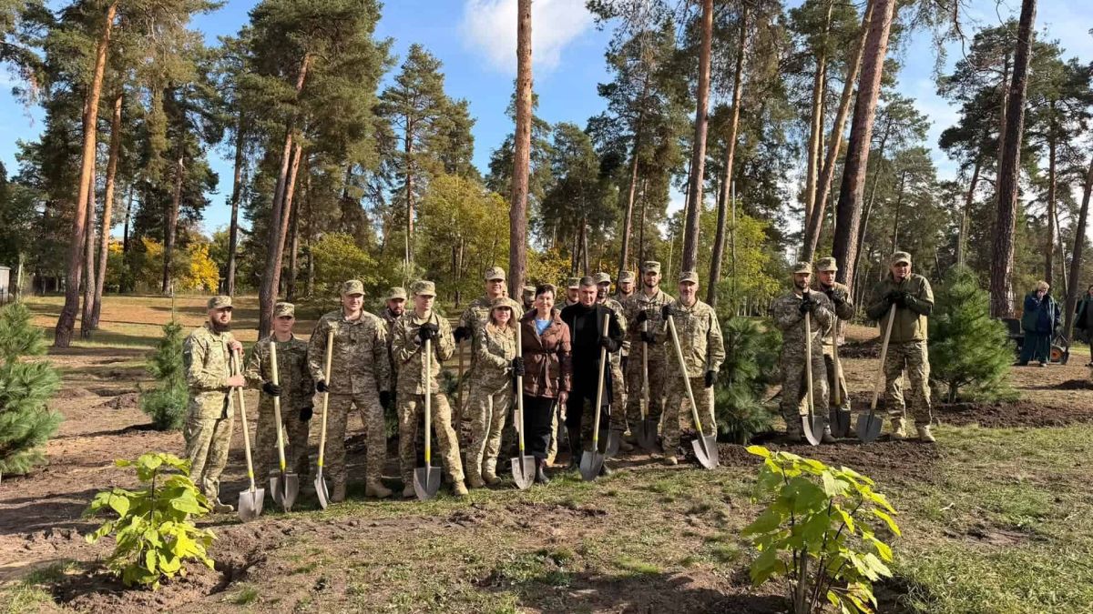 Військові, працівники КП і посадовці з лопатами після висадки молодих сосен у парку «Партизанська слава» в Дарницькому р-ні
