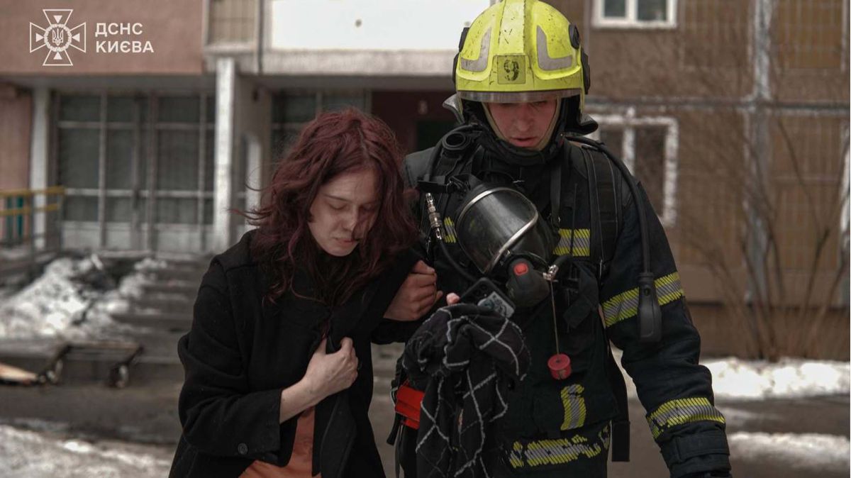 Рятувальник ДСНС Києва евакуює постраждалу жінку після пожежі у багатоповерхівці на вулиці Чорнобильській у Святошині