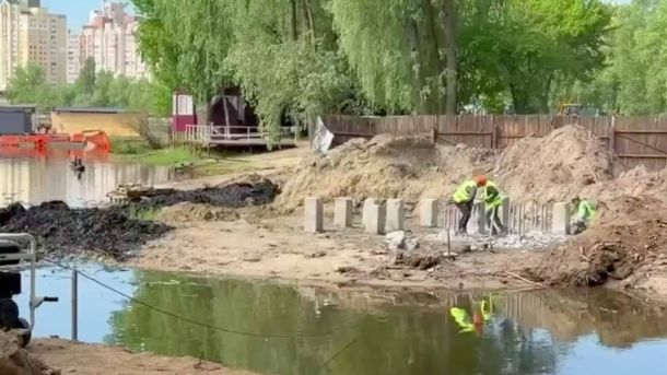 Будівельники зводять пішохідний міст через заводь у парку на вулиці Прирічній в Оболонському районі Києва