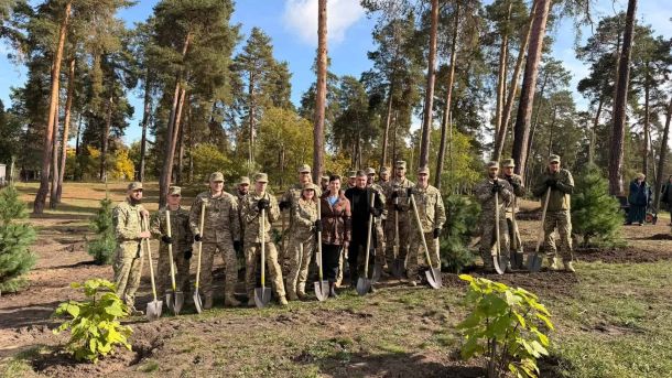 Військові, працівники КП і посадовці з лопатами після висадки молодих сосен у парку «Партизанська слава» в Дарницькому р-ні