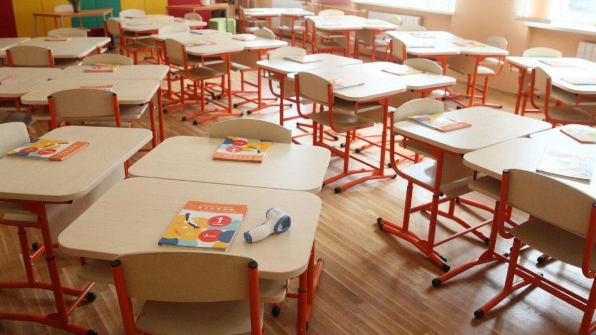 Порожній шкільний клас із партами на червоних ніжках та підручниками для першого класу, учнів немає — школи перейшли на дистанційне навчання