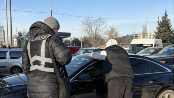 Поліцейський і підозрюваний біля автомобіля