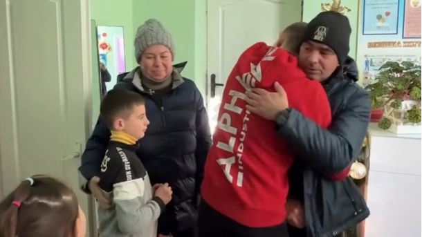 Батько обіймається зі старшим сином, лівіше – мати поряд з молодшим