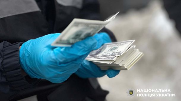 Руки криміналіста в синіх рукавичках тримають грошові купюри доларів