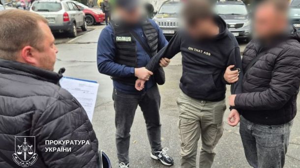 На вулиці четверо людей, троє з них - працівники поліції, двоє з них тримають підозрюваного у правопорушенні за руки