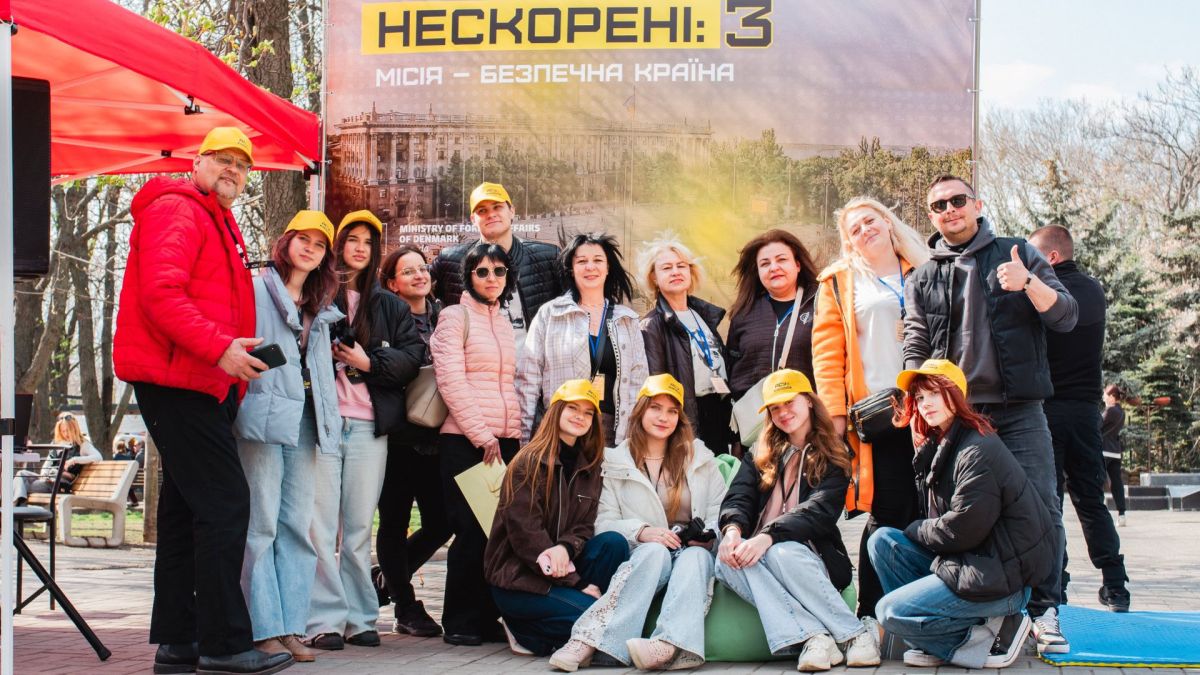 Учасники квесту «Нескорені: місія — безпечна країна» фотографуються на тлі банера заходу з мінної безпеки у Києві 4 квітня 2026 року