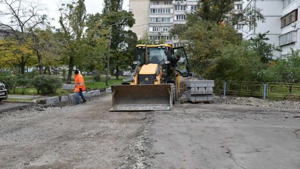 Велика дорожня техніка працює у дворі багатоповерхівок в Києві і ремонтує дорожнє покриття