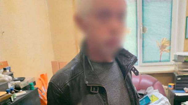 Чоловік у чорній шкіряній куртці з розмитим обличчям у поліцейському відділку — підозрюваний у розгромі кав'ярні у Шевченківському районі Києва