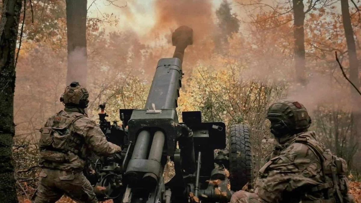 Двоє військових видять біля гармати в осінній лісопосадці і стріляють з неї