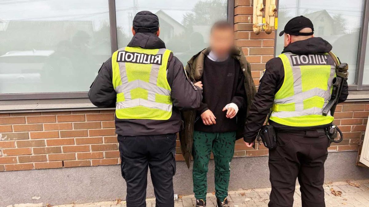 Двоє працівників поліції тримають під руки чоловіка в зелених штанях і темній куртці