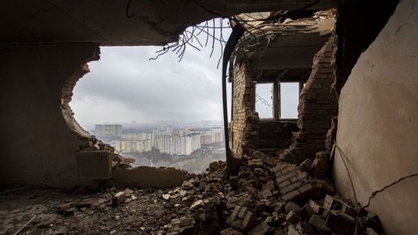 Банк «Сенс» відновить пошкоджений офіс у Києві: 113 млн на ремонт фасаду Зруйнований будинок у Києві з відкритим вікном, що відкриває панорамний вид на міські жовто-блакитні багатоповерхівки, зруйнований під час бойових дій, руйнування та обламки цегли.