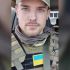 Головні новини Києва | Kyiv.News Портрет військового Романа Ратушного у бронежилеті з нашивкою прапора України, на тлі салону автомобіля