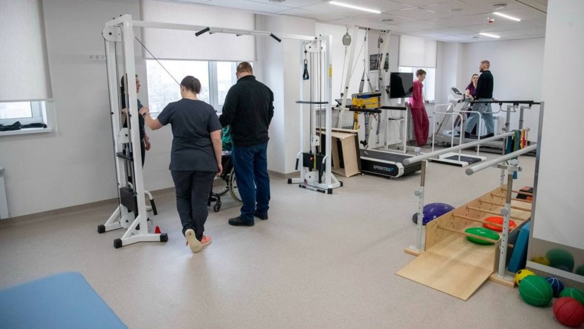 Зал фізичної реабілітації з тренажерами, де пацієнти проходять відновлення під наглядом фахівців: бігові доріжки, блокові тренажери, сходи та м'ячі для вправ