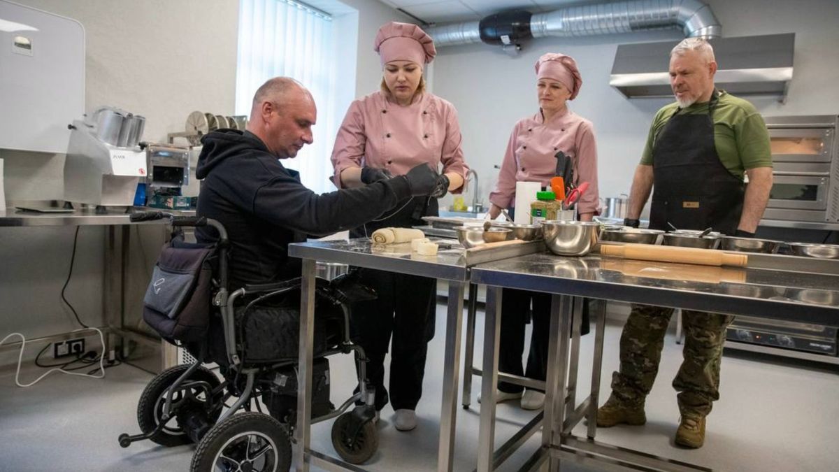 Учасники реабілітаційного центру Аскольд у Києві під час занять у кулінарній майстерні, чоловік на візку готує разом з інструкторами