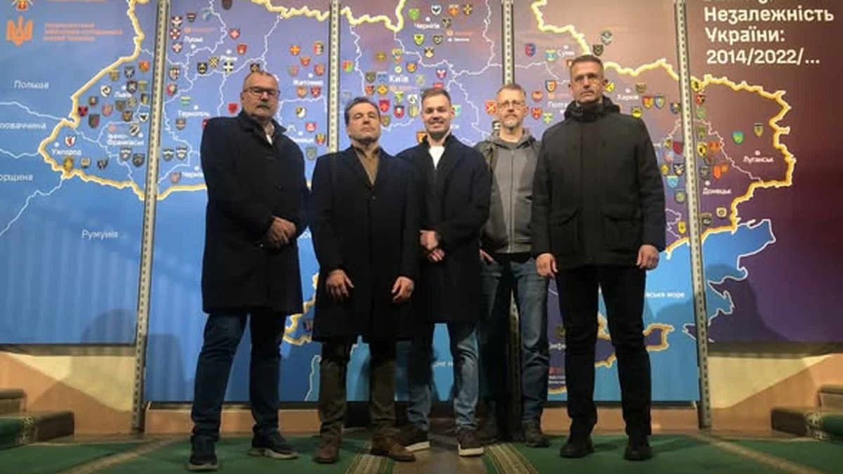 П'ятеро чоловіків стоять на фоні карти України на виставці Національного військово-історичного музею