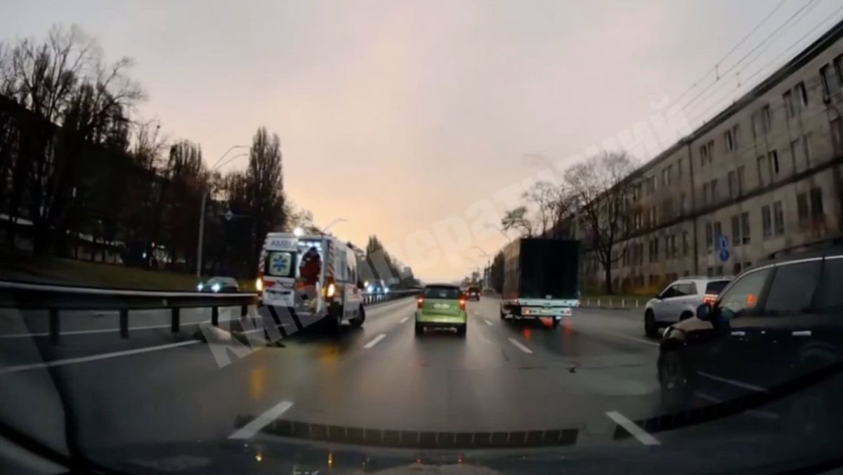 Вид із машини на мокру дорогу, де видно "швидку" та інші автомобілі під час сутінок