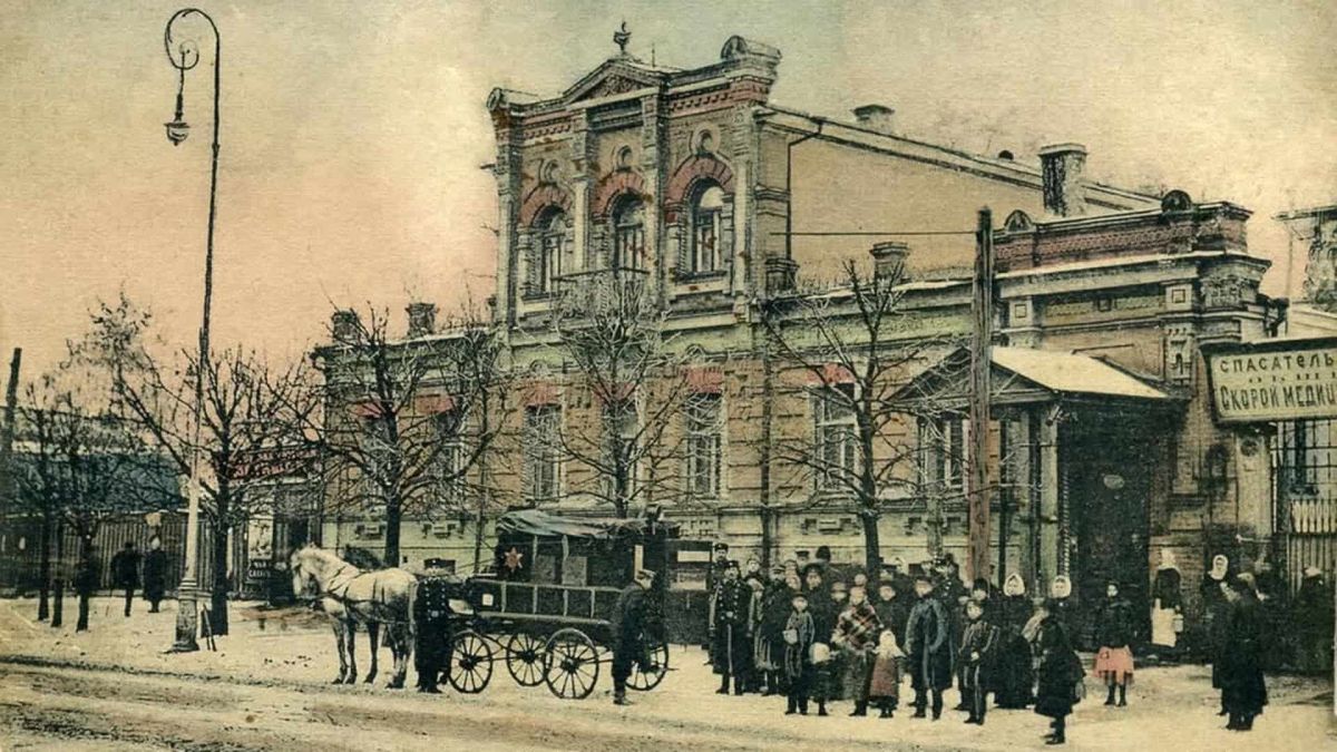 Історична листівка початку XX століття: будівля станції швидкої медичної допомоги на Володимирській, 33 у Києві, кінний екіпаж і перехожі