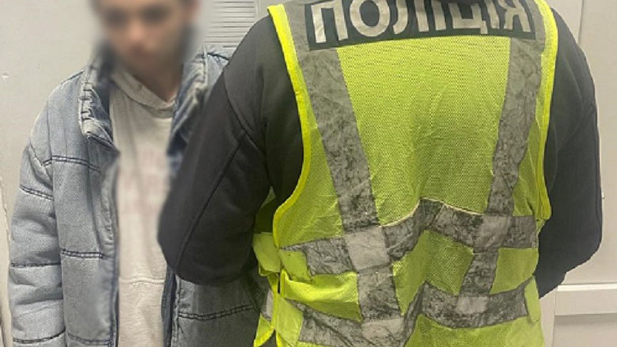Поліцейський у жилеті з написом «Поліція» поруч із затриманою 26-річною мешканкою Троєщини у відділі поліції Києва