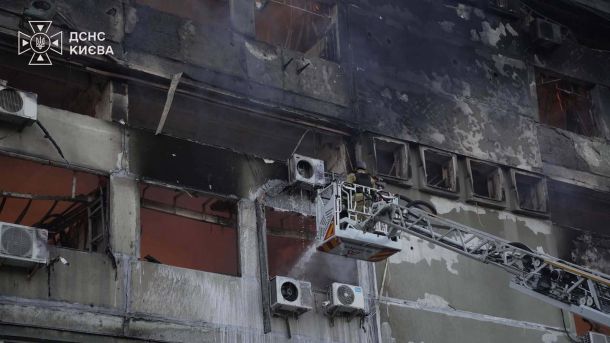Рятувальник ДСНС з автодрабини гасить займання у вигорілій багатоповерховій будівлі після атаки на Київ