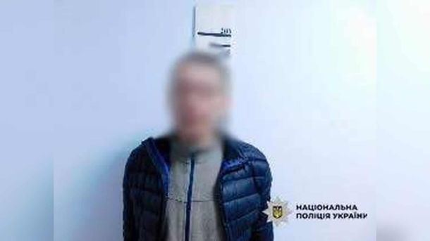 Затриманий 38-річний киянин у синій куртці з розмитим обличчям на тлі стіни, у кутку — логотип Національної поліції України