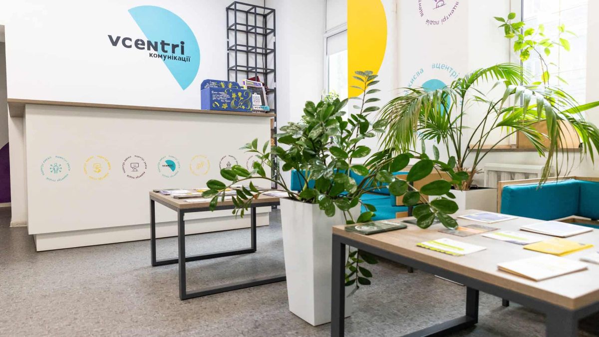 Інтер'єр громадського простору Vcentri HUB зі стійкою реєстрації, столами з інформаційними матеріалами та кімнатними рослинами
