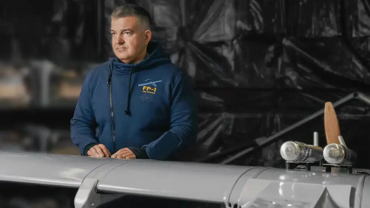 Чоловік у синій кофті з логотипом FP-1 UAV System стоїть поруч із далекобійним дроном FP-1 компанії Fire Point